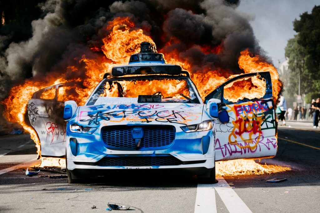 A Waymo car burns in the street as smoke billows during protests in Los Angeles, California, on June 8, 2025.